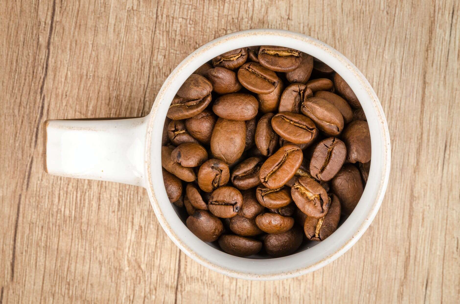 roasted coffee beans inside white ceramic mug